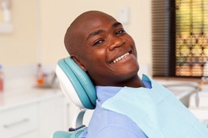 Man smiling in dentla chair after dental checkup and teeth cleaning
