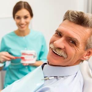 Older man in dental chair during restorative dentistry visit smiling