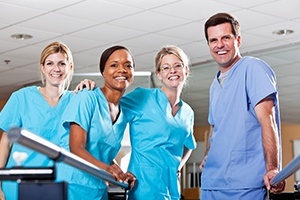 Four smiling dentists wearing blue scrubs