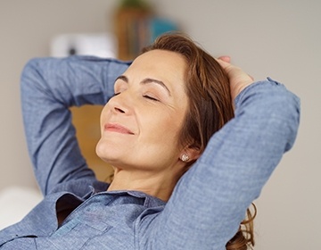 Relaxing woman with arms behind head after sedation dentistry visit