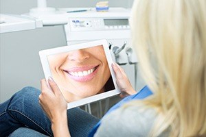 Woman looking at her virtual smile design on tablet computer