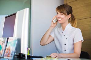 Receptionist answering call for Belmont emergency dentist