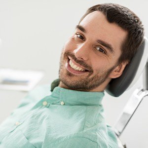 Man in dental chair smiling after tooth extractions