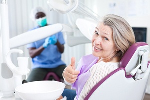 Happy patient giving thumbs up after successful implant salvage treatment