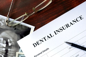 Dental insurance form next to X-Ray and glasses