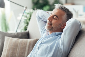 Man resting at home, following dental implant post-op instructions