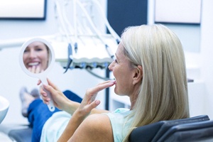 Dental patient using mirror to admire new prosthetic teeth