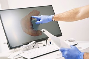 Dentist holding digital impression wand and pointing at computer monitor