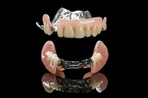 Upper and lower partial dentures against black background