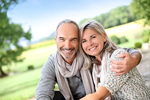 Senior couple sitting outside, enjoying benefits of partial dentures