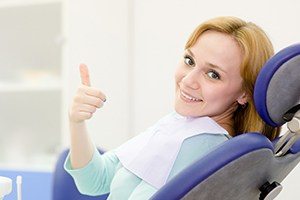 Woman smiling and giving thumbs up after one visit dental restoration