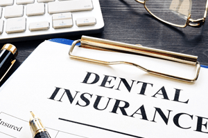 Dental insurance form on clipboard next to keyboard