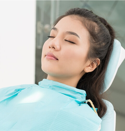 Young woman lying in dental chair with eyes closed
