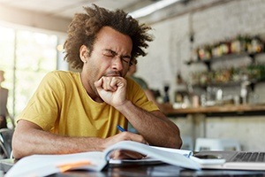 Man in need of sleep apnea treatment yawning at work