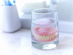Caring for dentures by storing them in glass of water