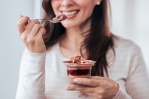 Woman eating pudding after wisdom tooth extractions