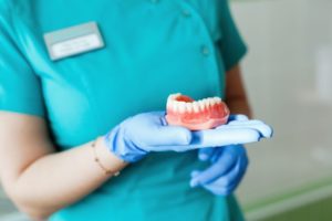 Dental professional holding denture in gloved hand